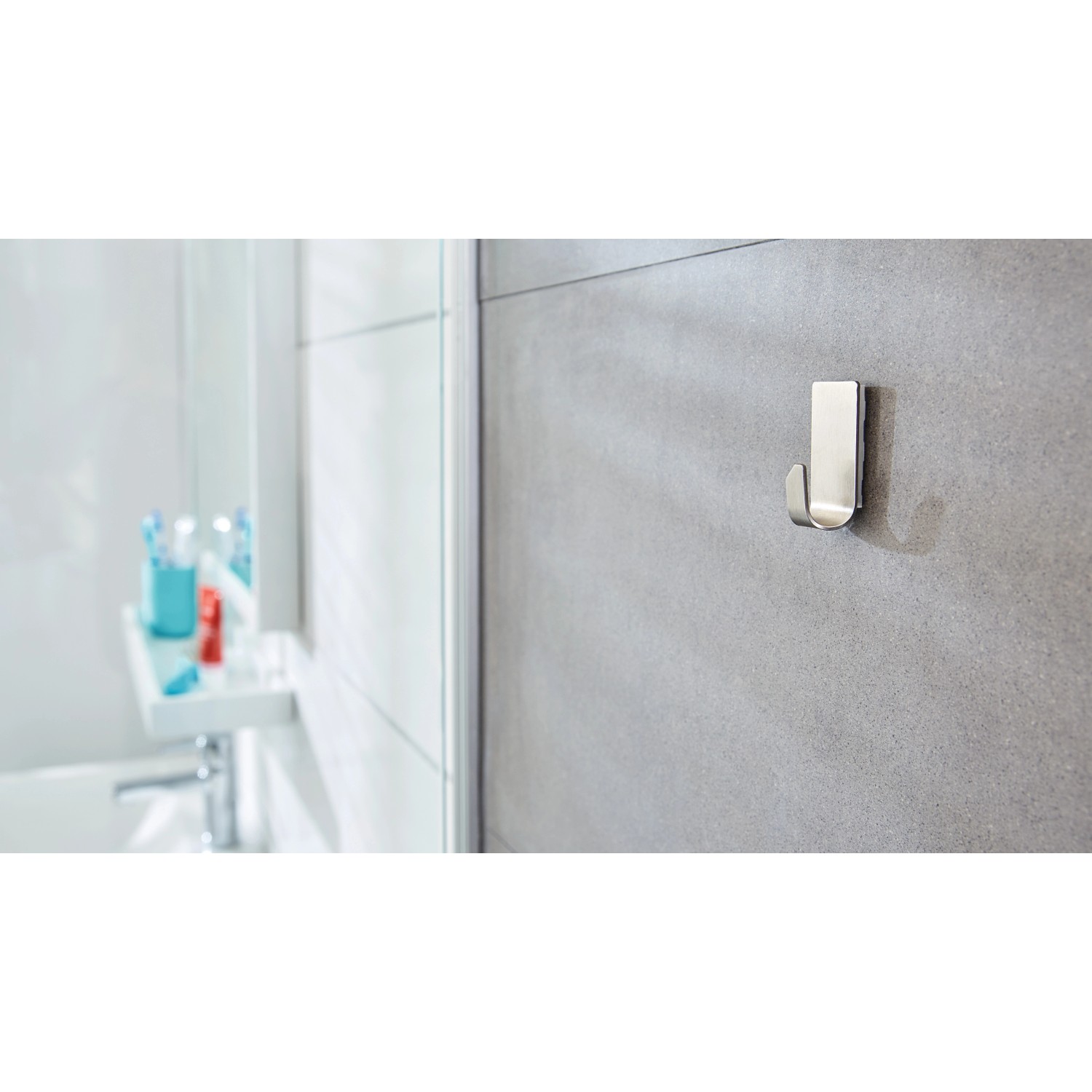 Tesa Powerstrips Haken Waterproof Zoom Edelstahl Small, 2er-Pack, an grauer Badezimmerwand.