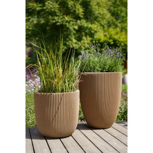 Zwei beige Capi Europe Blumentöpfe Kugel Groove mit Pflanzen auf einer Holzterrasse.