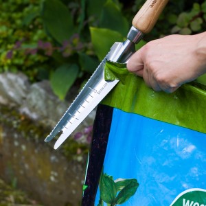 Kent & Stowe Multifunktions-Unkrautjäter im Einsatz: Öffnen eines Sackes Pflanzerde mit gezackter Klinge.