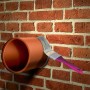 Anwendung von MEM Dicht-Fix Bauabdichtung auf Rohr mit Pinsel an Backsteinwand.