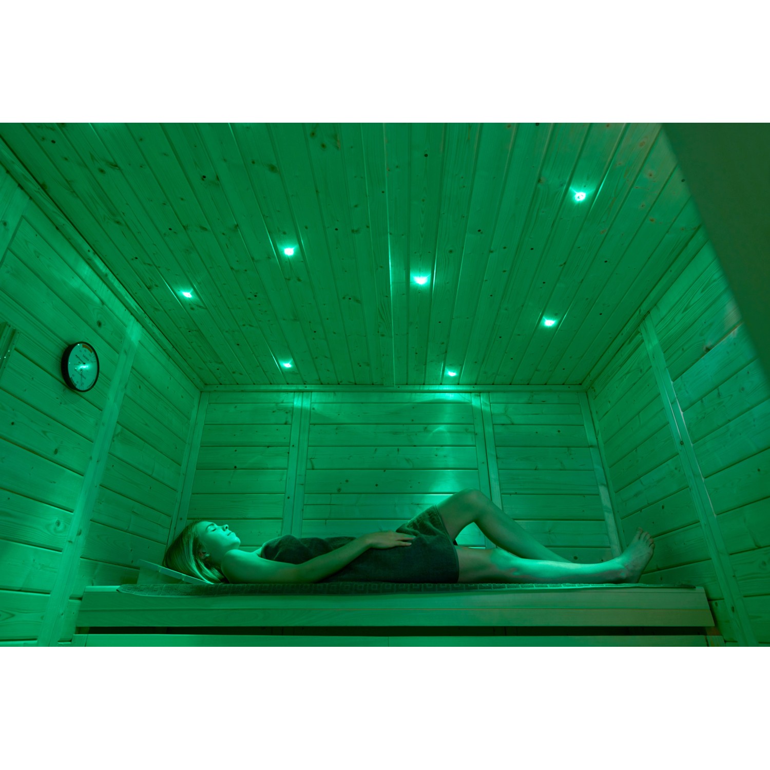 Frau entspannt in Weka Massivholzsauna Kemi Panorama mit Farbvisionen-Set A und 7,5 kW Saunaofen.