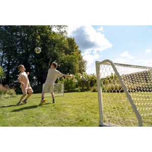 Zwei Kinder spielen mit dem Exit Fußballtor Scala Aluminium 120x80 cm im Garten.