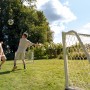 Zwei Kinder spielen mit dem Exit Fußballtor Scala Aluminium 120x80 cm im Garten.