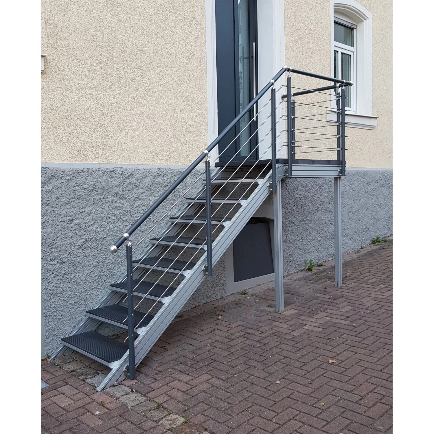 Treba Außentreppe Alaska 3 mit 6 Stufen, Aluminium, mit Geländer vor Hauswand.