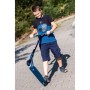 Lachender Junge fährt blauen Six Degrees Stuntscooter mit Wing-Lenker auf gepflastertem Weg. Sport & Fitnessgerät.