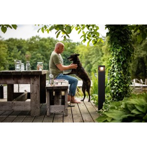 Philips myGarden Parterre LED-Wegeleuchte in Schwarz neben Mann mit Hund im Garten.