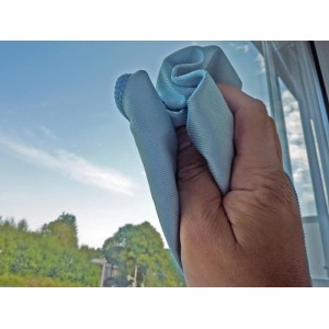 Hand wischt Fenster mit blauem Mikrofasertuch aus Unger Glasreinigungsset.