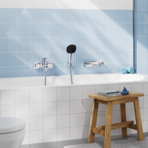 Grohe Einhand-Wannenarmatur Dice Chrom, wandmontiert, mit Handbrause in modernem Bad mit blauen Fliesen.
