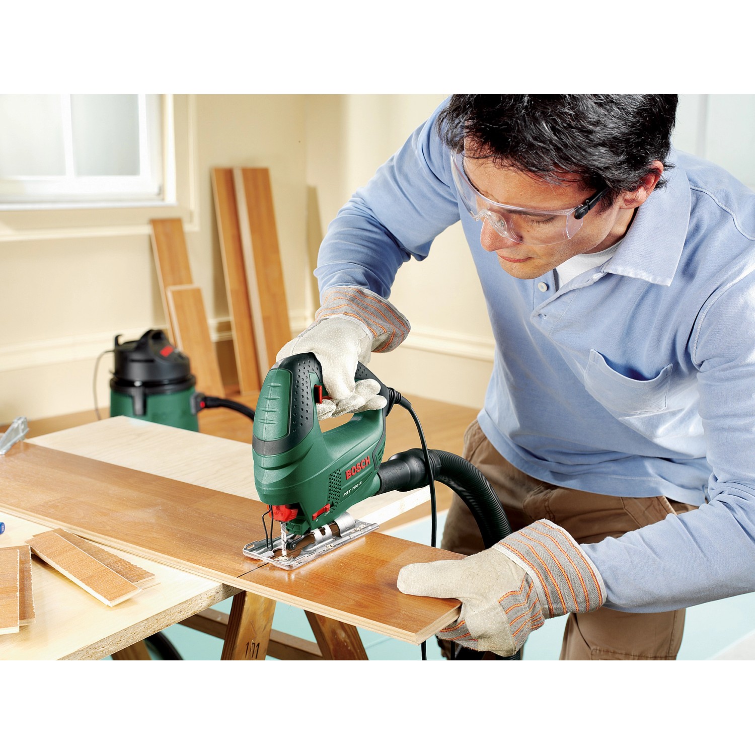 Bosch Stichsäge PST 700 E in Aktion beim Sägen von Holz. Kompakte grüne Säge mit Mann im Bild.