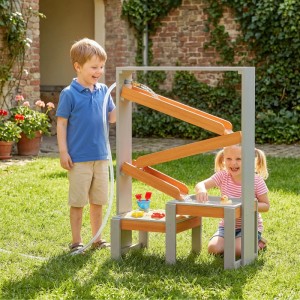 Kinder spielen mit AIYAPLAY Sand- & Wasserspieltisch aus Tannenholz im Garten. Grauer Rahmen, Holzbahnen, zwei Becken.