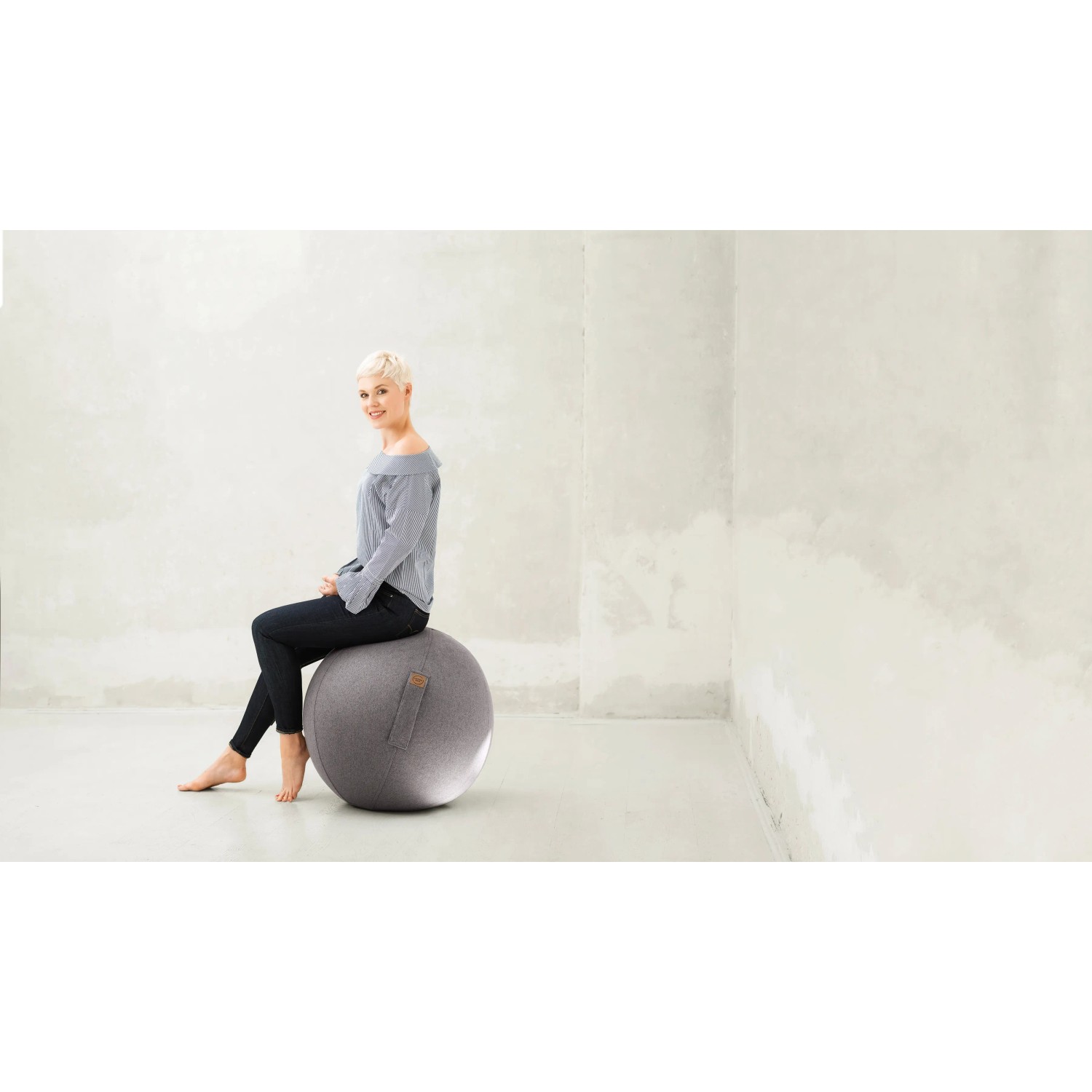 Frau sitzt auf grauem Sitting Ball Hocker Felt 150 l. Bequemer Sitzsack für Wohnzimmer.