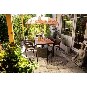 Gartenmöbel-Set mit braunen Polyrattan Stapelstühlen Davenport und Holztisch unter Sonnenschirm.