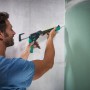 Mann appliziert Silikon mit wolfcraft Kartuschenpresse MG 400 auf Wand. Ergonomisches Maurer- & Verlegewerkzeug.