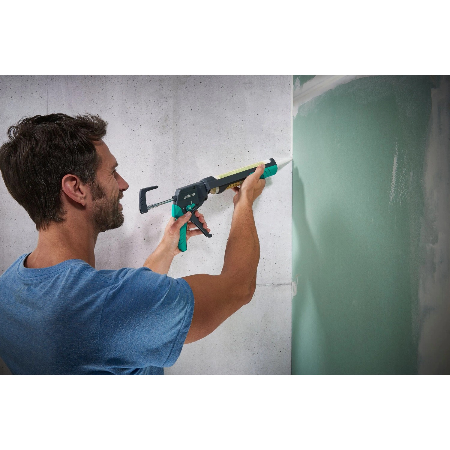 Mann appliziert Silikon mit wolfcraft Kartuschenpresse MG 400 auf Wand. Ergonomisches Maurer- & Verlegewerkzeug.