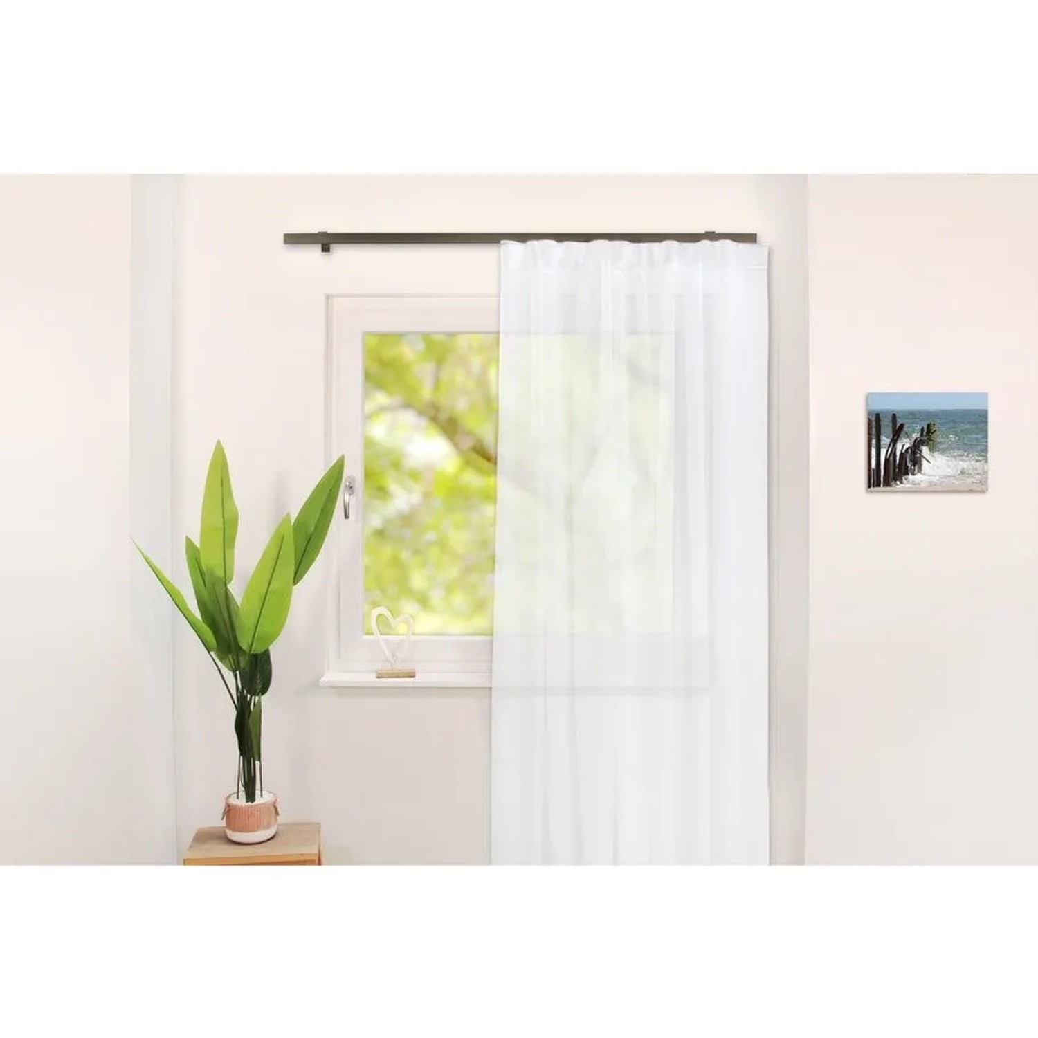 Einläufige Gardinenschiene in Edelstahl-Optik über einem Fenster mit weißem Vorhang. Modernes Wohnaccessoire.