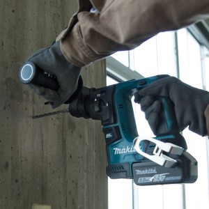Makita Bohrhammer beim Bohren in Betonwand. Akku-Bohrhammer aus dem 17-teiligen Meißel- und Bohrer-Set.