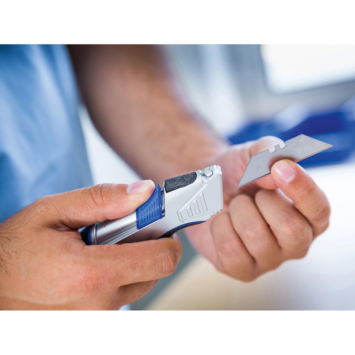 LUX Cuttermesser mit Tasche und Klinge in der Hand, silberfarben mit blauem Griff.