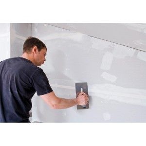 Mann spachtelt Wand mit Knauf Uniglett Innenspachtel (20 kg).