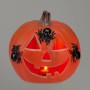 Oranger Halloween-Kürbis mit leuchtendem Gesicht und drei schwarzen Spinnen. Dekorative Figur für Halloween.