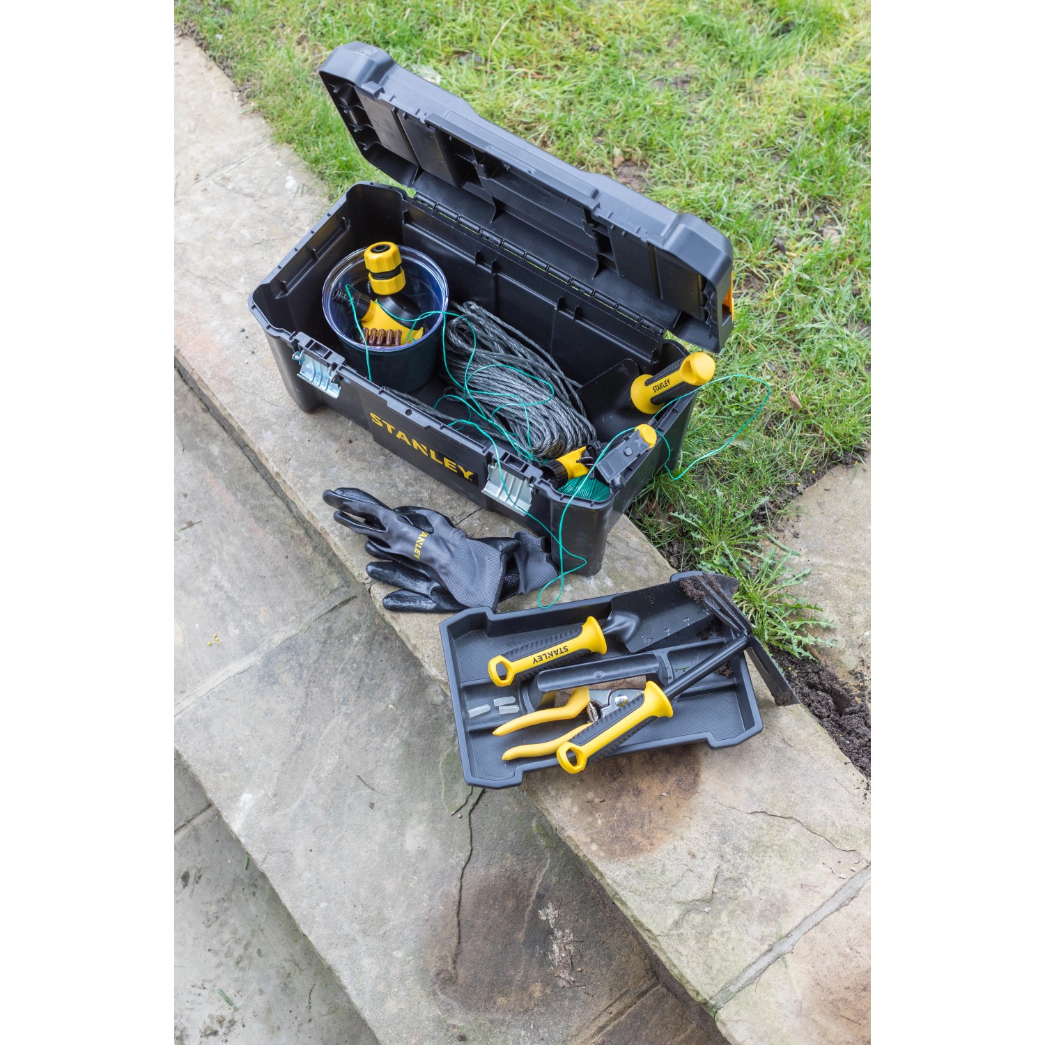 Offene Stanley Werkzeugbox 19 Zoll mit Werkzeug, Handschuhen und Zubehör auf Steinstufen.