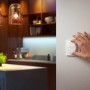 Weißer Philips Hue Tap Dial Schalter an Wand, bedient von Hand. Smarte Lichtsteuerung.