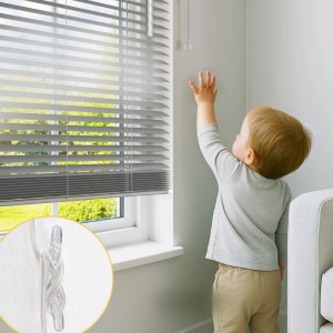 Silberne Sol Royal Alu Jalousie am Fenster, Kind greift nach Zugschnüren. Detailansicht der Kindersicherung.