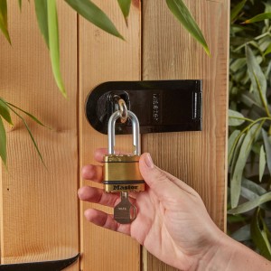 Master Lock Excell Vorhängeschloss, 2er-Pack. Laminiertes Messing Schloss mit Schlüssel in Hand an Holztür.
