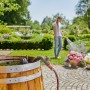 Gardena Regenfasspumpe 4000/1 im Einsatz: Frau bewässert Garten mit Regenwasser aus Holzfass.