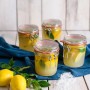 Dr. Oetker Bügelverschlussgläser (530 ml) gefüllt mit Zitronen und Kräutern auf blauem Tuch.