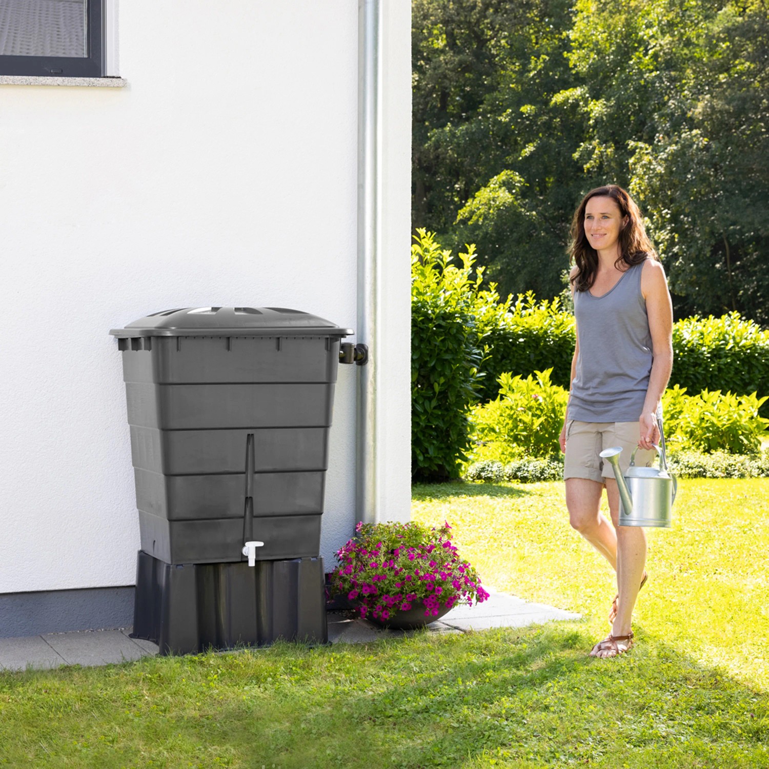 Garantia Regentonnen-Unterstand Eckig 300 l Graphite Grey mit Frau und Gießkanne im Garten.