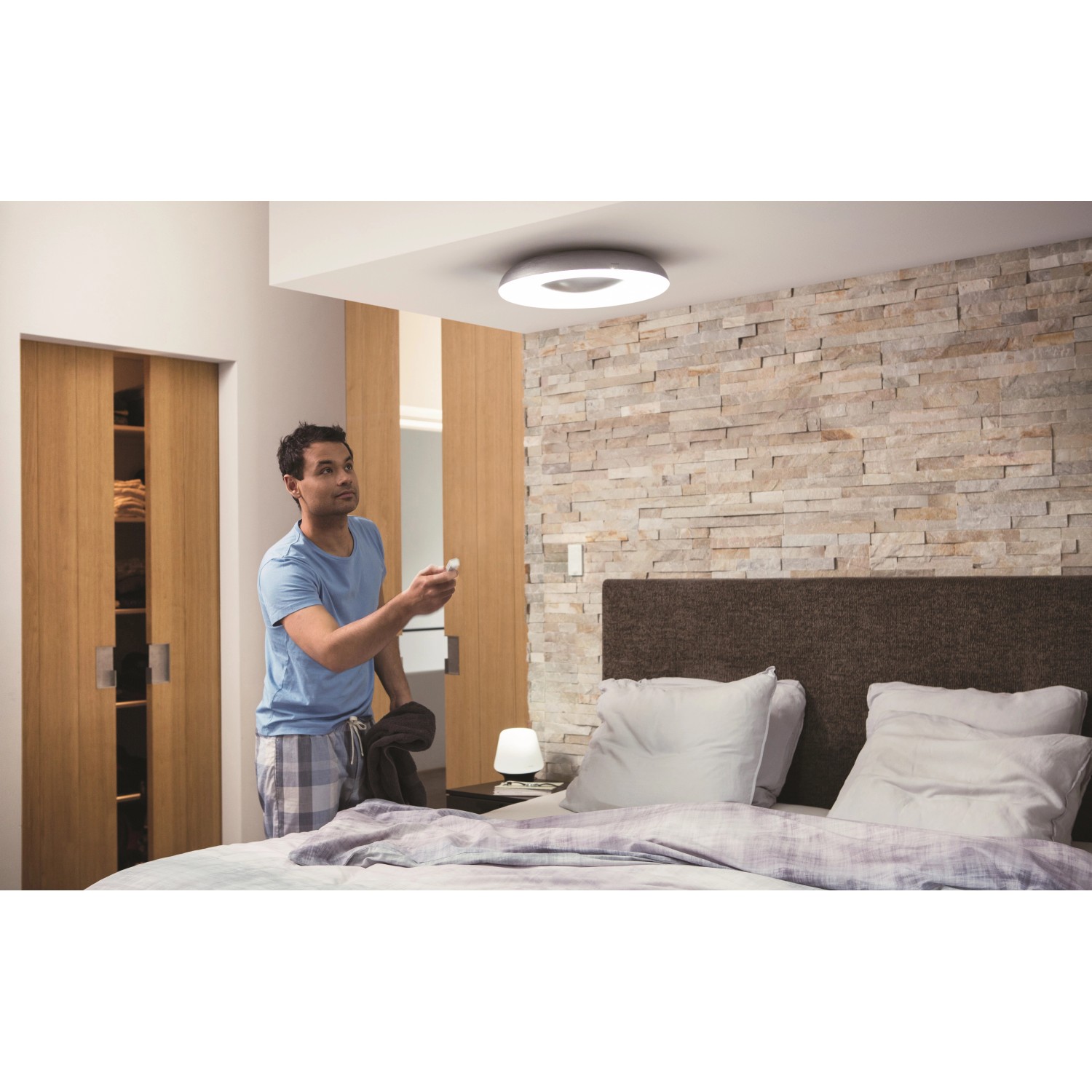 Schwarze Philips Hue White Ambiance Still Deckenleuchte mit Dimmer in einem Schlafzimmer.
