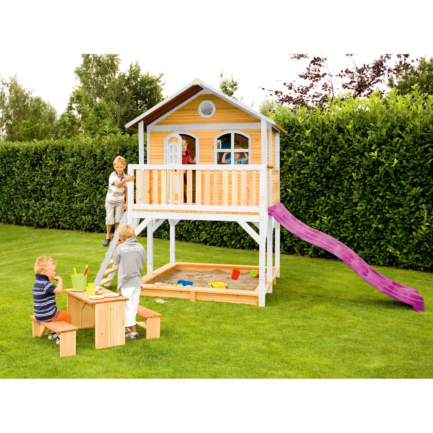 Axi Marc Spielhaus aus Holz mit lila Rutsche, Sandkasten und Picknicktisch im Garten.