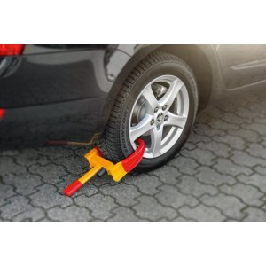 Basi Radkralle KFZ 105 am Reifen eines Autos. Diebstahlsicherung für Autoanhänger in Rot und Gelb.