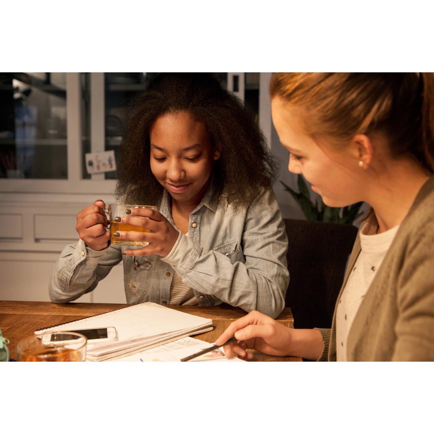 Szene mit zwei jungen Frauen an einem Tisch, beleuchtet durch ein Philips LED-Leuchtmittel.