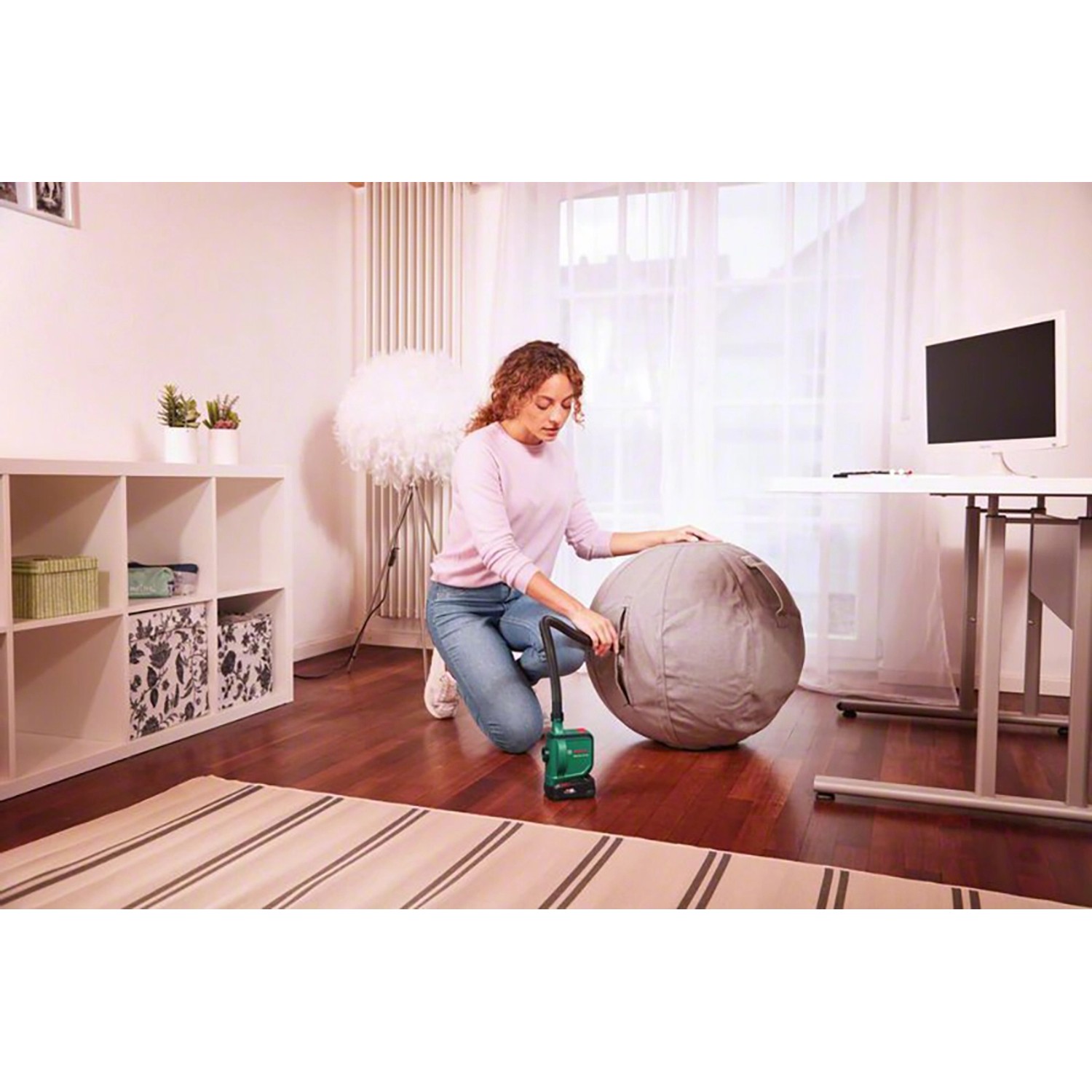 Frau pumpt grauen Gymnastikball mit Bosch Akku-Luftpumpe EasyInflate 18V-500 Solo auf.