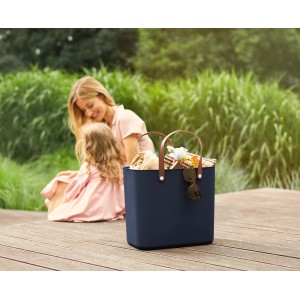 Dunkelblaue Rotho Multibag Style Albula 25 l mit braunen Griffen und Inhalt vor Mutter und Kind.