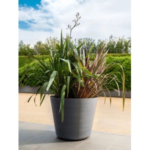 Großer, grauer Deroma Pflanztopf Original (Ø 48 cm) mit Pflanzen im Garten. Handgefertigt, frost- & UV-beständig.
