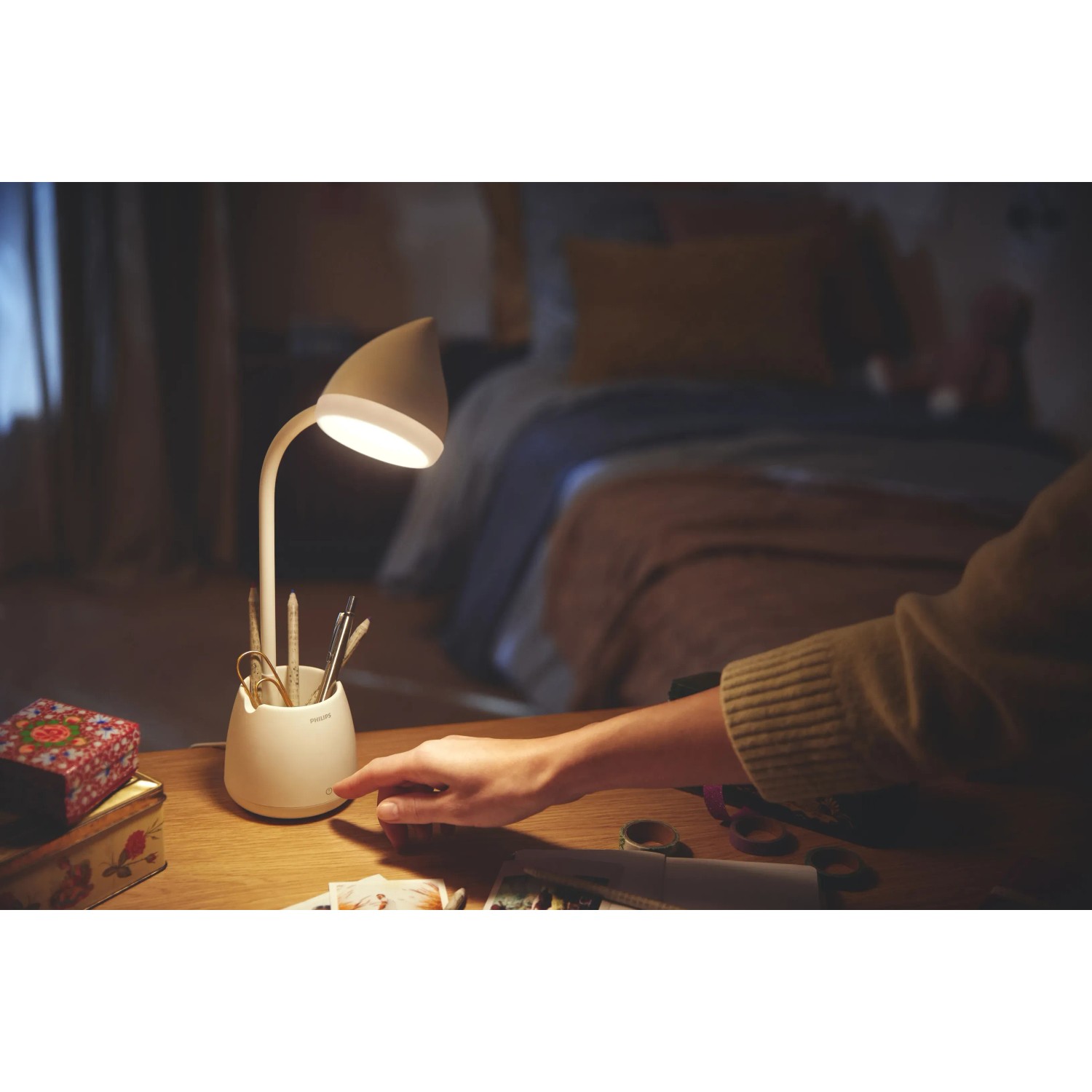 Weiße Philips LED Schreibtischleuchte Hat mit Stiftehalter und Hand am Schalter.