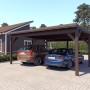 Holzbrüder Doppelcarport Ralf, graubraun, mit Blechdach in Dunkelbraun und zwei geparkten Autos.