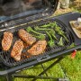 Weber Traveler Camping-Gasgrill mit Steaks und Brokkoli auf dem Grillrost.