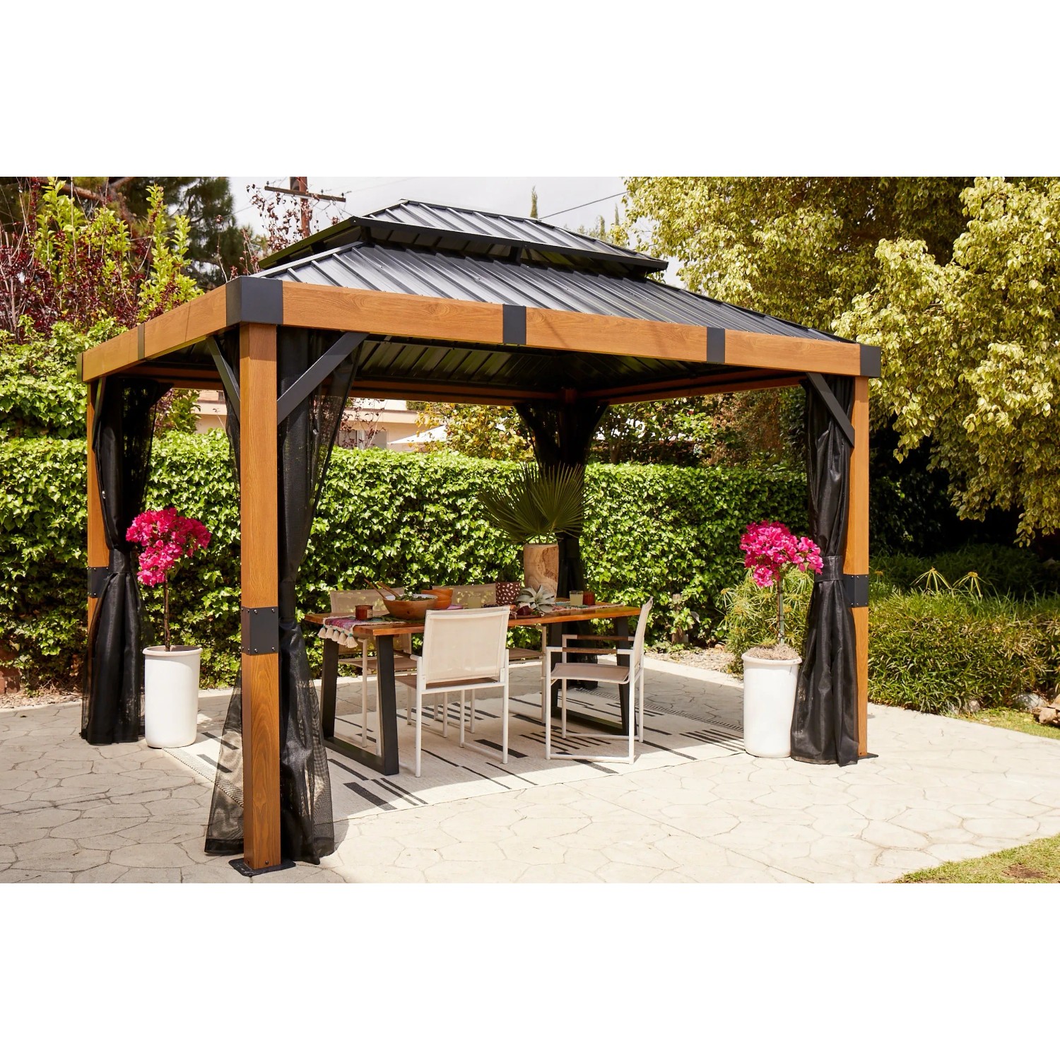 Sojag Pavillon Fontana 289x363 cm mit Moskitonetz und Esstisch im Garten.