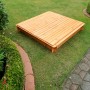 Quadratischer Sandkasten Donald 140x140 cm mit geschlossenem, klappbarem Holzdeckel im Garten.