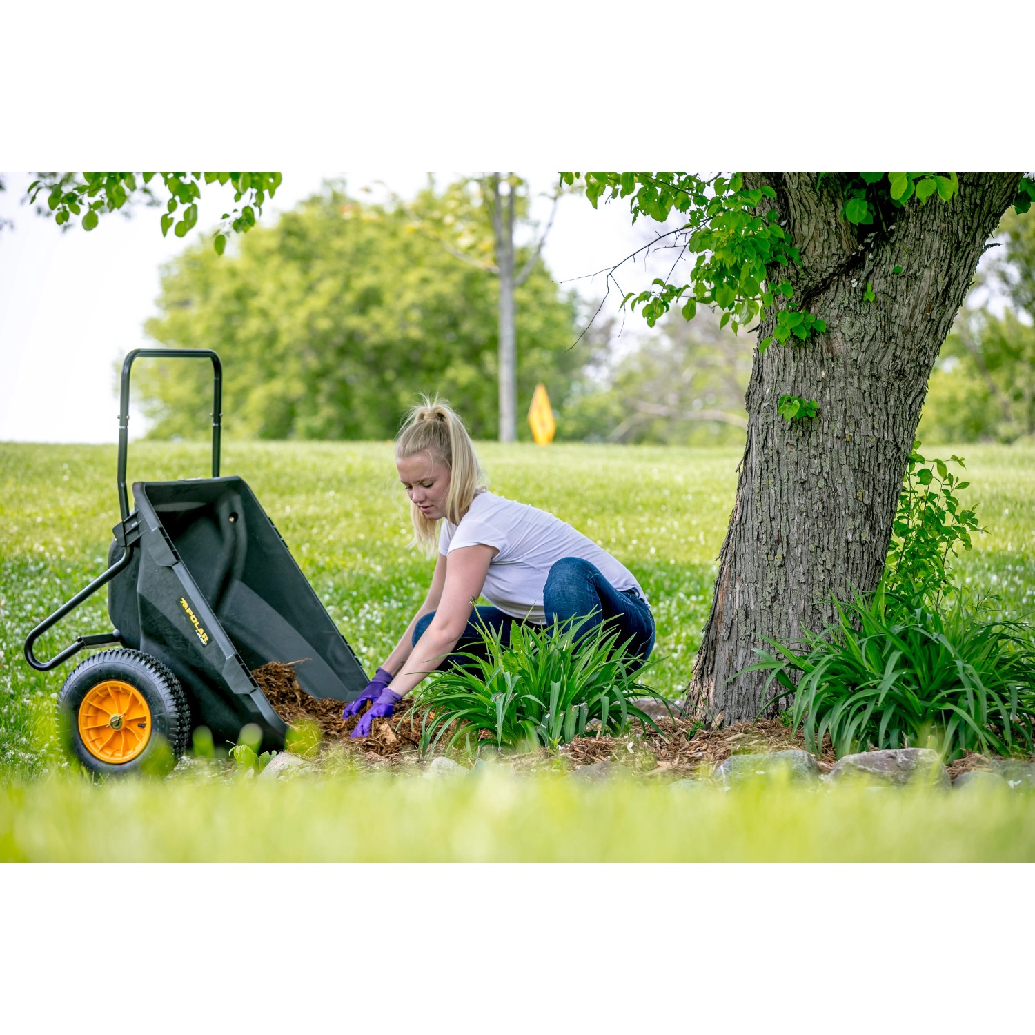 Schwarze Polar Cub Cart Schubkarre (127x71cm) im Einsatz bei Gartenarbeit.