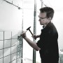 Handwerker stemmt Fliesen mit Wera Schraubendreher-Set und Hammer von der Wand.