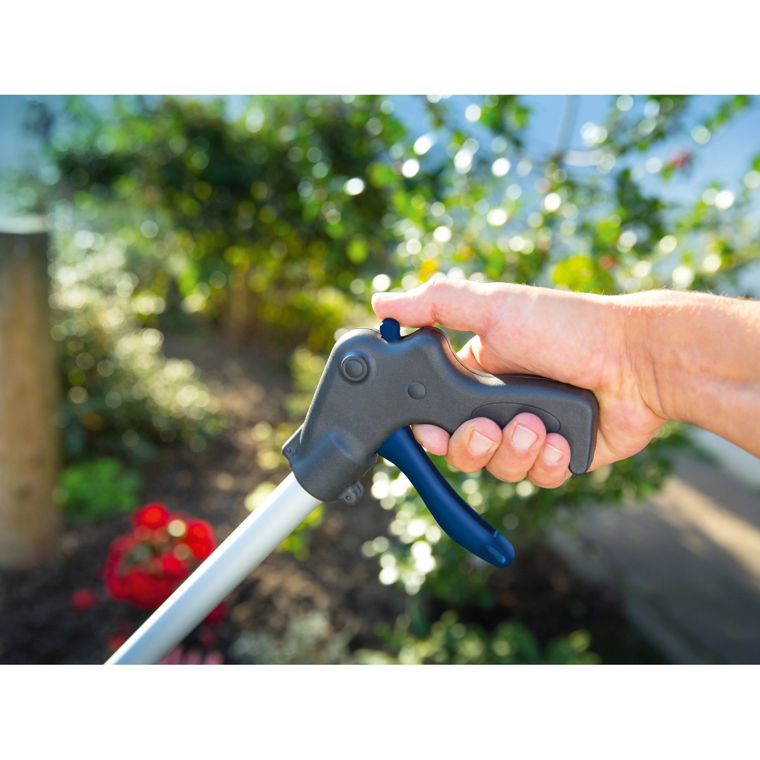 LUX Müllgreifer 87 cm in Aktion: Hand betätigt den Griff zum Aufsammeln von Gartenabfällen.