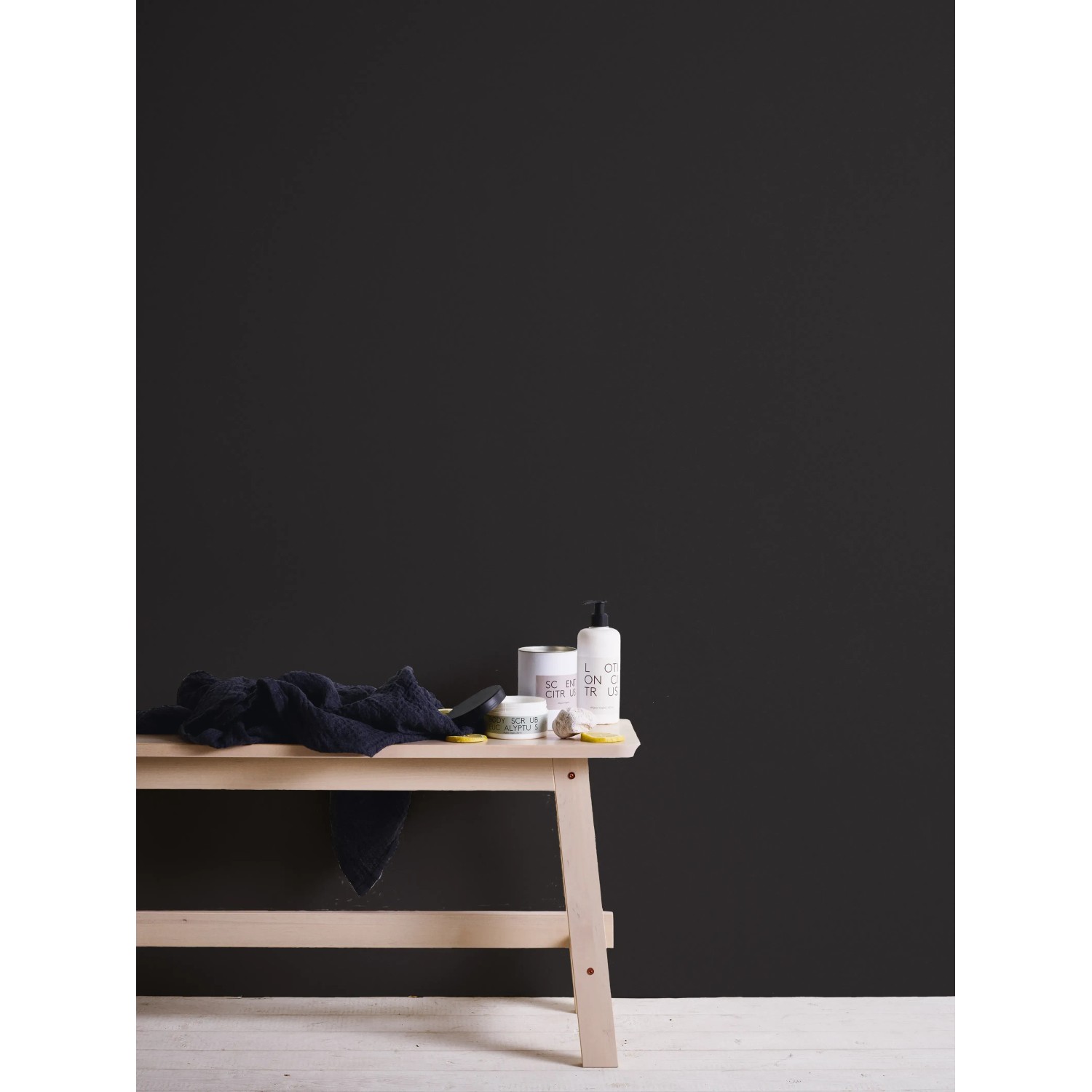 Schwarze Vliestapete Trendwall 2 Uni von A.S. Création an Wand hinter Holzhocker.