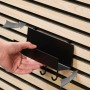 Schwarzes DenPanels Regal mit 4 Stiften (21,5 cm) wird an einer Akustikpaneelwand montiert.