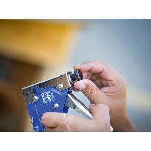 LUX Handtacker Classic: Blaue Metall-Ausführung mit verstellbarem Knopf in Händen.