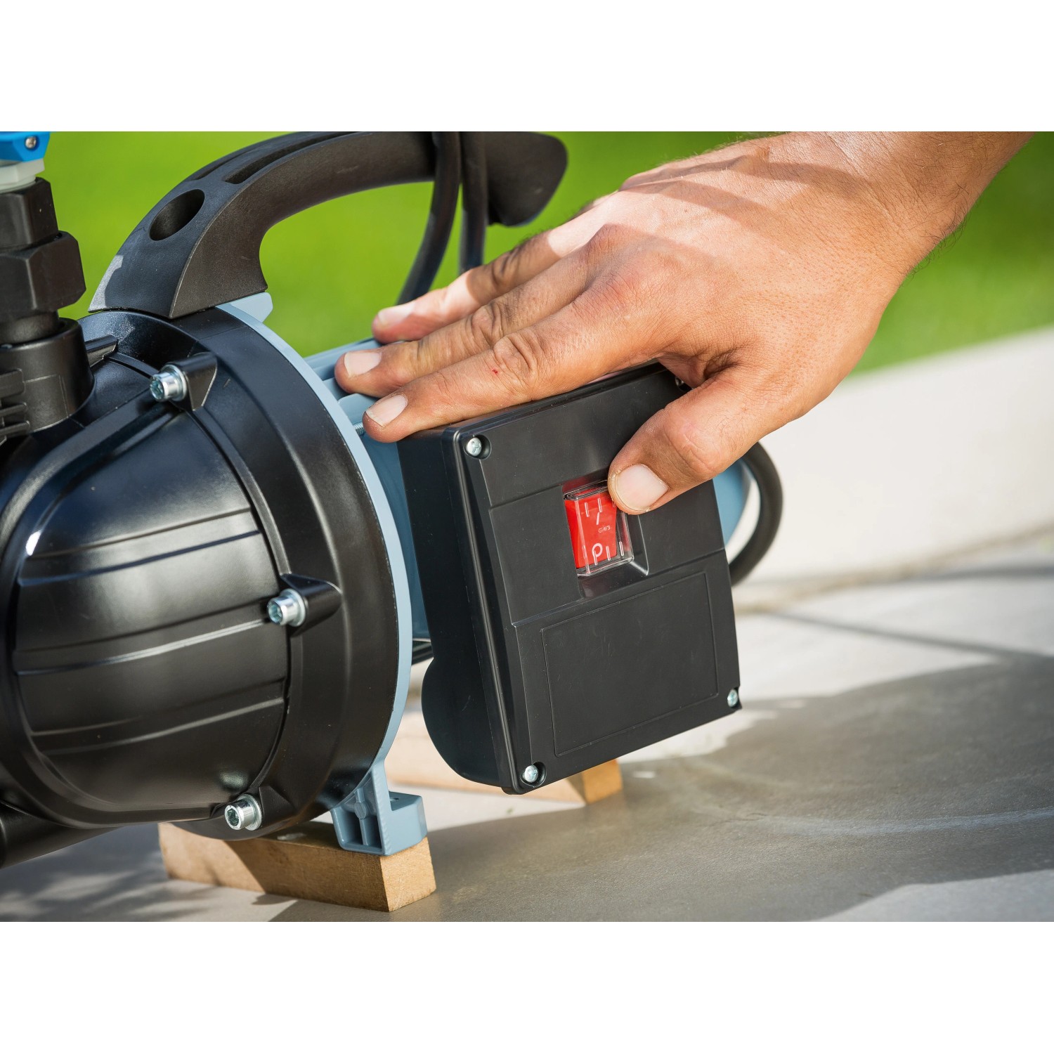 Nahaufnahme: Hand betätigt roten Schalter am elektronischen Druckschalter EDS 8 für Gartenpumpen.