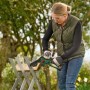 Frau sägt Holz mit Bosch Akku-Gehölzschneider EasyChain 18V. Hochentaster für Gartenarbeiten.